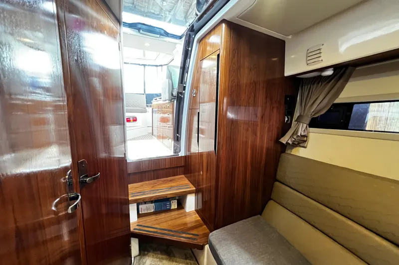 Slide: The Image of Interior of 2024 Aquador 300 HT boat, featuring wooden finishes and cozy seating area. - 47