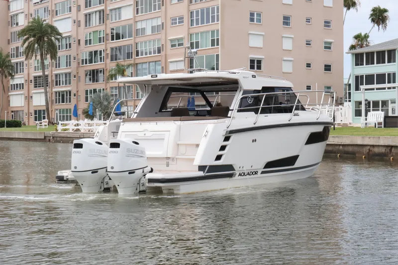 Slide: The Image of 2024 Aquador 300 HT boat with dual Suzuki engines on a calm waterway. - 8