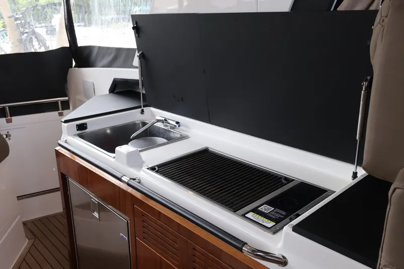 Slide: The Image of 2024 Aquador 300 HT yacht kitchenette with sink, grill, and storage. - 32
