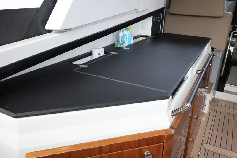 Slide: The Image of 2024 Aquador 300 HT yacht interior with sleek black countertop and wooden cabinetry. - 31