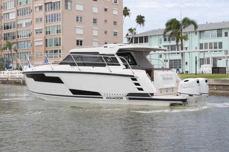 Slide: The Image of 2024 Aquador 300 HT boat cruising near waterfront buildings. - 12