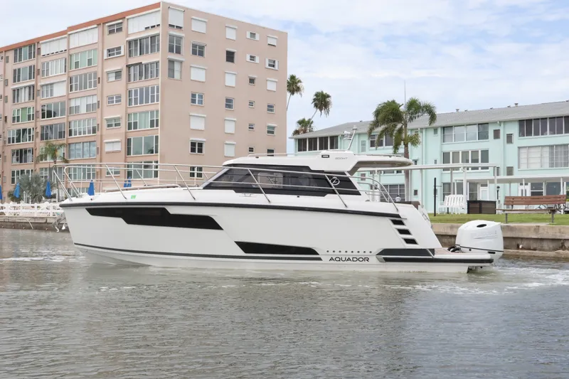 Slide: The Image of 2024 Aquador 300 HT boat cruising near waterfront buildings. - 10