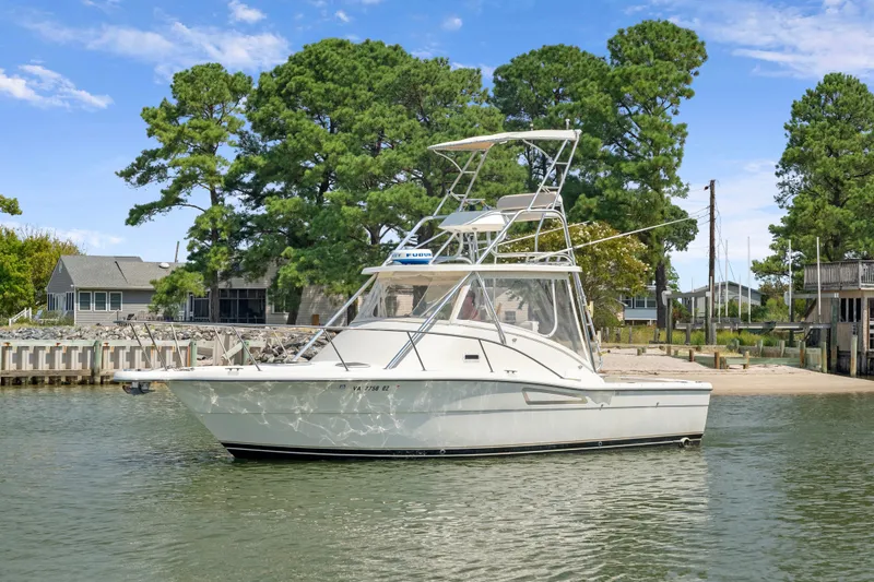 The Image of 1995 Pursuit 3000 Offshore boat docked near a waterfront property. - 0