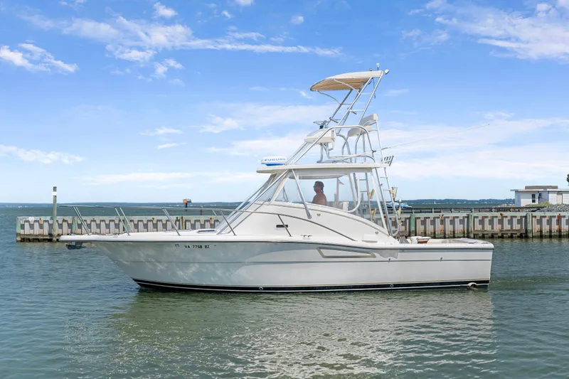 Slide: The Image of 1995 Pursuit 3000 Offshore boat docked in calm waters under a clear blue sky. - 59