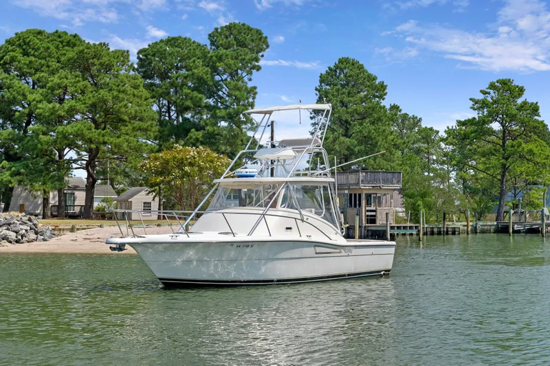 Slide: The Image of 1995 Pursuit 3000 Offshore boat docked near lush green trees. - 50