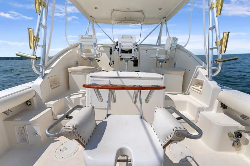 Slide: The Image of 1995 Pursuit 3000 Offshore boat interior with seating and fishing rod holders on open water. - 20