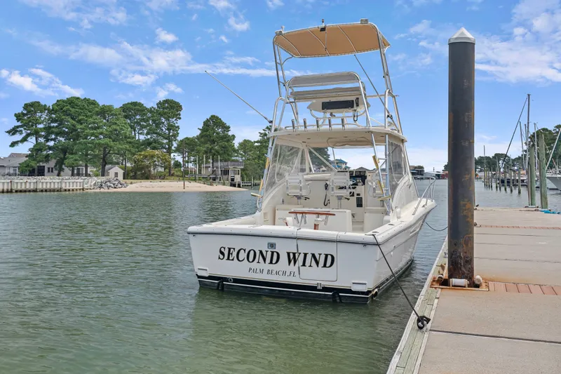 Slide: The Image of 1995 Pursuit 3000 Offshore boat docked, named "Second Wind," in a serene marina setting. - 45
