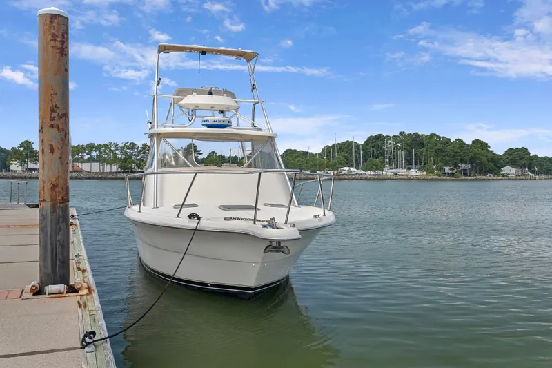 Slide: The Image of 1995 Pursuit 3000 Offshore boat docked on calm water under a clear blue sky. - 49