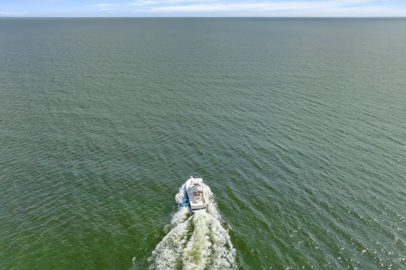 Slide: The Image of Aerial view of 1995 Pursuit 3000 Offshore boat cruising on open water. - 62