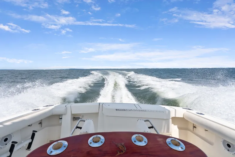 Slide: The Image of 1995 Pursuit 3000 Offshore boat cruising on open water under clear blue sky. - 35