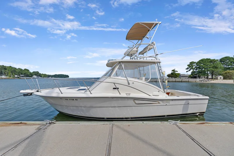 Slide: The Image of 1995 Pursuit 3000 Offshore boat docked on a calm, scenic waterfront. - 51
