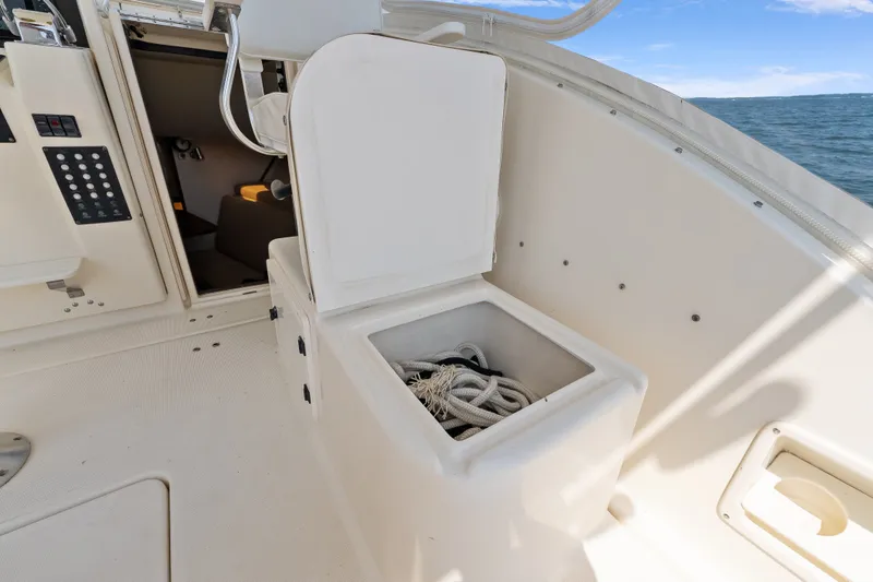 Slide: The Image of 1995 Pursuit 3000 Offshore boat interior with open storage compartment and visible ropes. - 28