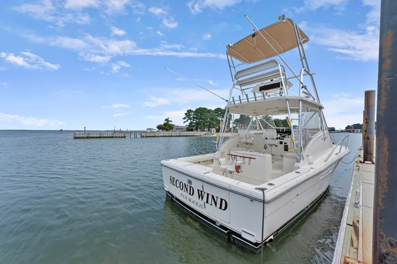 Slide: The Image of 1995 Pursuit 3000 Offshore boat docked, named "Second Wind," under a clear blue sky. - 47