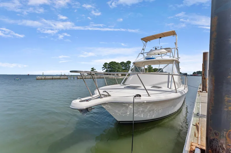 Slide: The Image of 1995 Pursuit 3000 Offshore boat docked on calm waters under a clear blue sky. - 53
