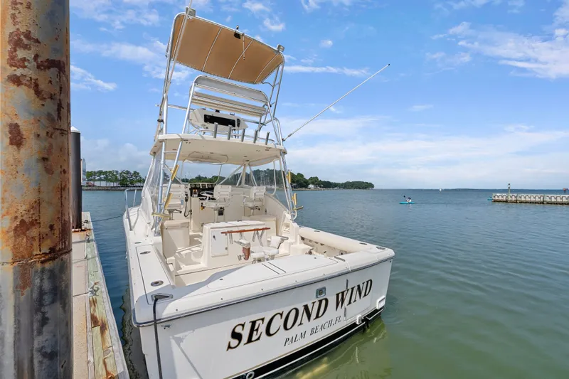Slide: The Image of 1995 Pursuit 3000 Offshore boat docked, named "Second Wind," with clear skies and calm waters. - 52