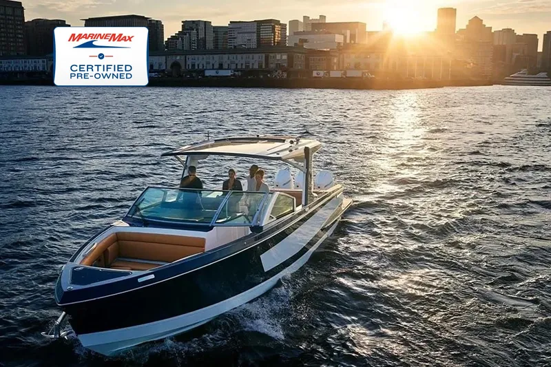 Slide: The Image of Aviara AV36 OB 2023 glides through the water at sunset, with a city skyline in the background. - 0