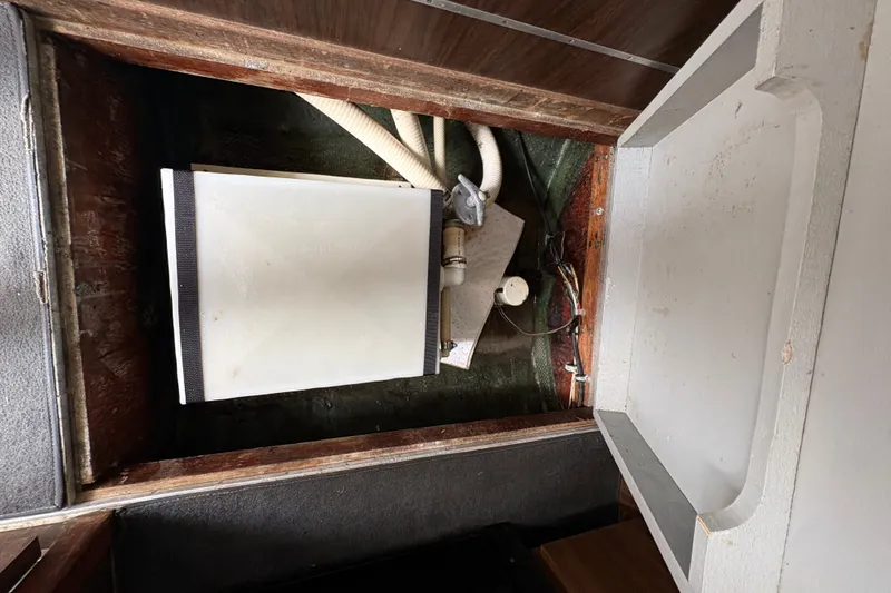 Slide: The Image of 1974 Bertram 31 Flybridge Cruiser interior showing storage compartment and plumbing components. - 40