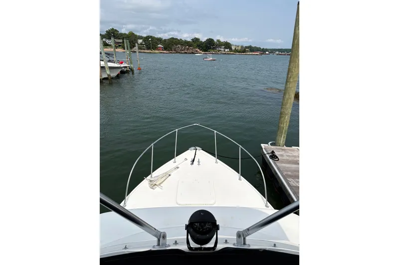 Slide: The Image of 1974 Bertram 31 Flybridge Cruiser docked by a scenic waterfront. - 24