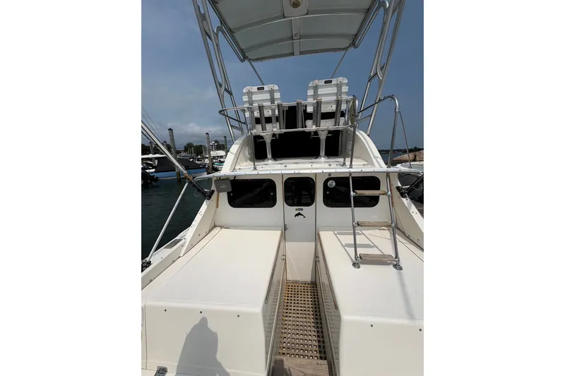 Slide: The Image of 1974 Bertram 31 Flybridge Cruiser, rear view, docked at marina under clear sky. - 17