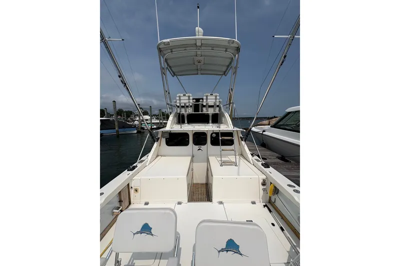Slide: The Image of 1974 Bertram 31 Flybridge Cruiser docked, showcasing spacious deck and fishing chairs. - 18