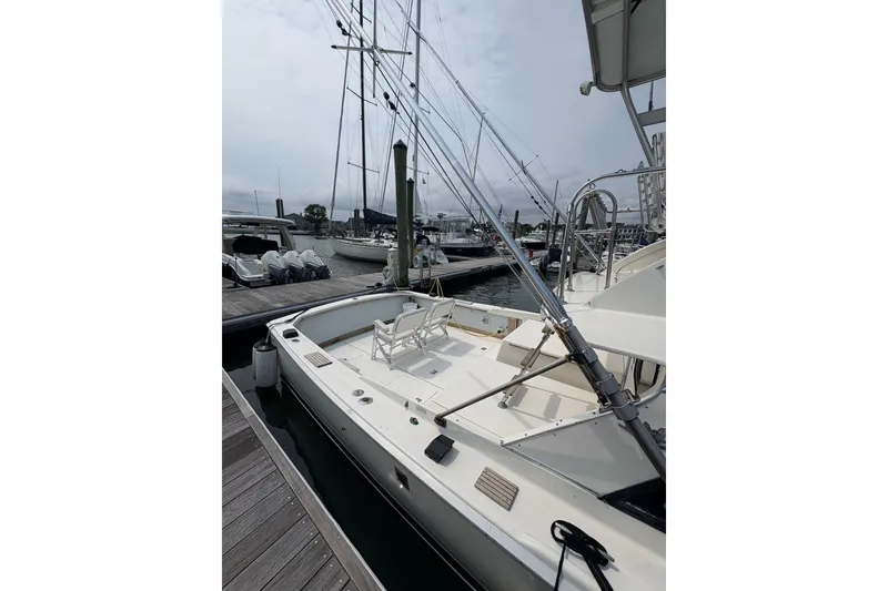 Slide: The Image of 1974 Bertram 31 Flybridge Cruiser docked at a marina, showcasing its spacious deck. - 16