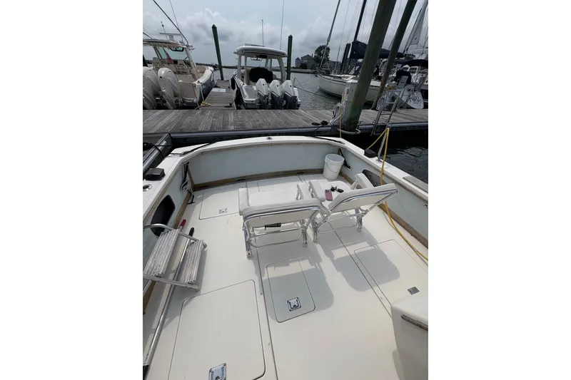 Slide: The Image of 1974 Bertram 31 Flybridge Cruiser docked, featuring spacious deck with chairs and equipment. - 15