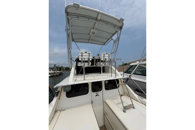 Slide: The Image of 1974 Bertram 31 Flybridge Cruiser with upper deck seating, docked at marina. - 20