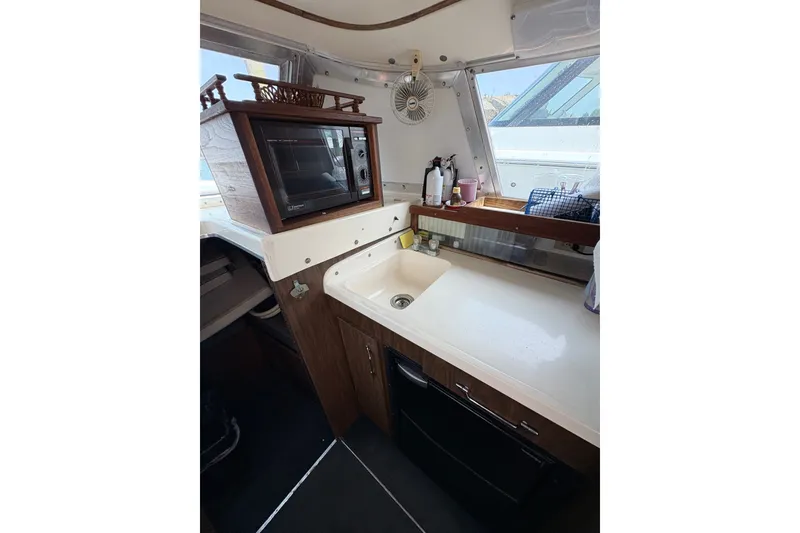 Slide: The Image of 1974 Bertram 31 Flybridge Cruiser interior with kitchenette, featuring a microwave and sink. - 30