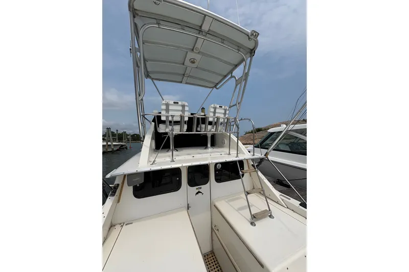Slide: The Image of 1974 Bertram 31 Flybridge Cruiser with ladder and seating, docked under a clear sky. - 19