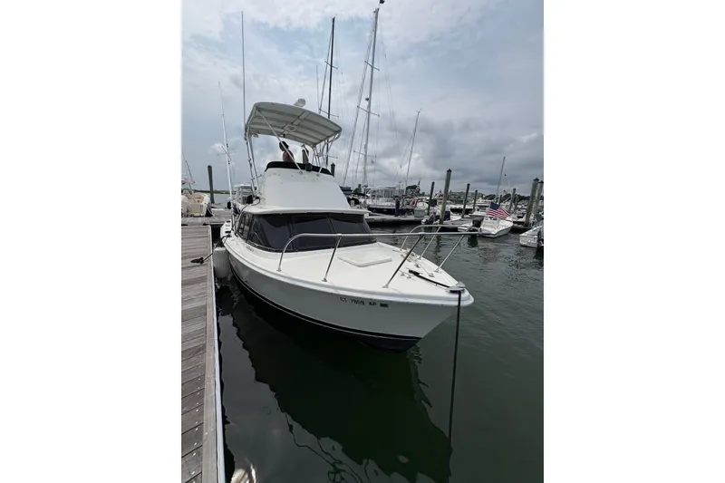 Slide: The Image of 1974 Bertram 31 Flybridge Cruiser docked at a marina, surrounded by other boats. - 11