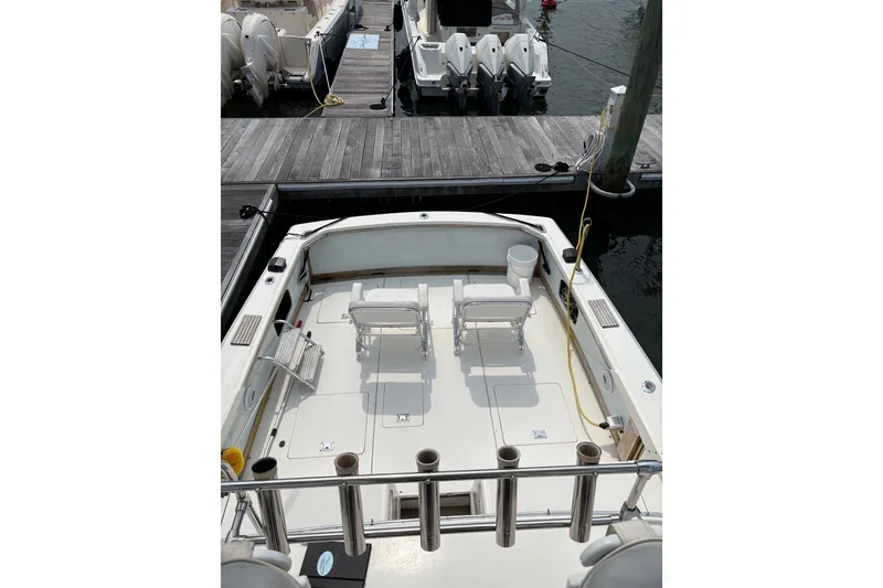 Slide: The Image of 1974 Bertram 31 Flybridge Cruiser docked, featuring spacious deck and seating area. - 13