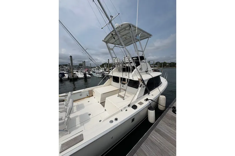 Slide: The Image of 1974 Bertram 31 Flybridge Cruiser docked at marina, showcasing spacious deck and flybridge. - 7