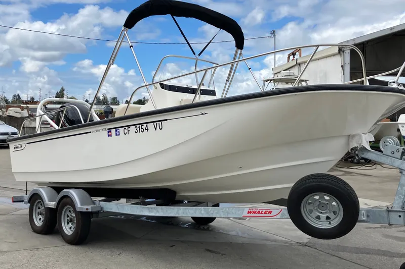 Slide: The Image of 2023 Boston Whaler 190 Montauk boat on trailer, parked outdoors under a cloudy sky. - 15