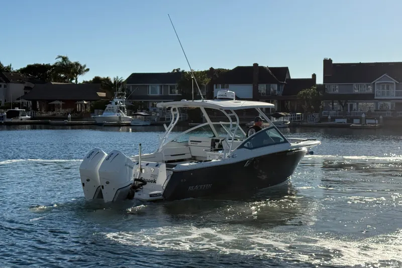Slide: The Image of 2022 Blackfin 272 DC boat cruising in a scenic waterfront neighborhood. - 6