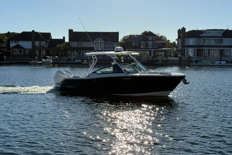 The Image of 2022 Blackfin 272 DC boat cruising on a sunny waterfront with houses in the background. - 0