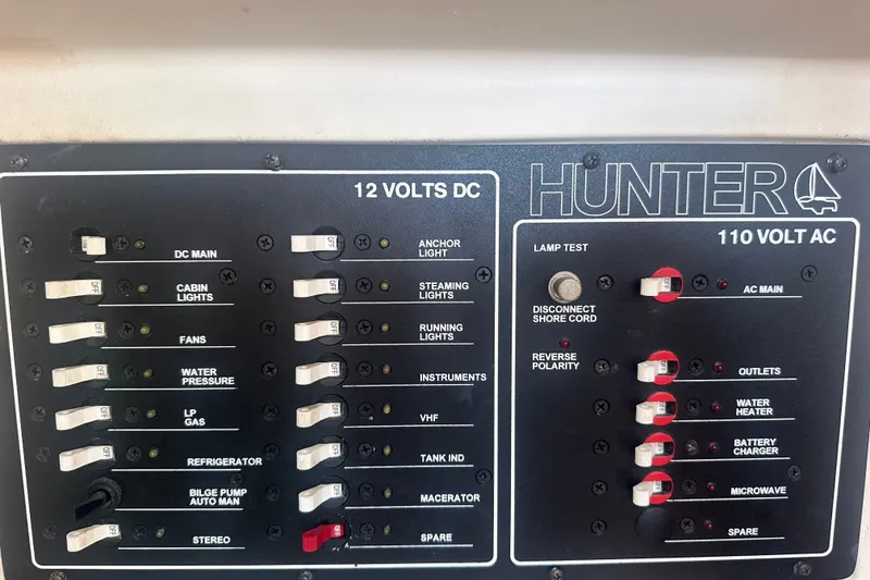 Slide: The Image of Electrical control panel of a 1997 Hunter 34 boat, featuring 12V DC and 110V AC switches. - 19
