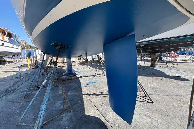 Slide: The Image of 1997 Hunter 34 sailboat on stands, showcasing blue-painted hull and keel in a boatyard. - 31