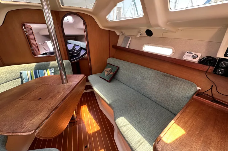 Slide: The Image of Interior of a 1997 Hunter 34 sailboat with wooden table and cushioned seating. - 24