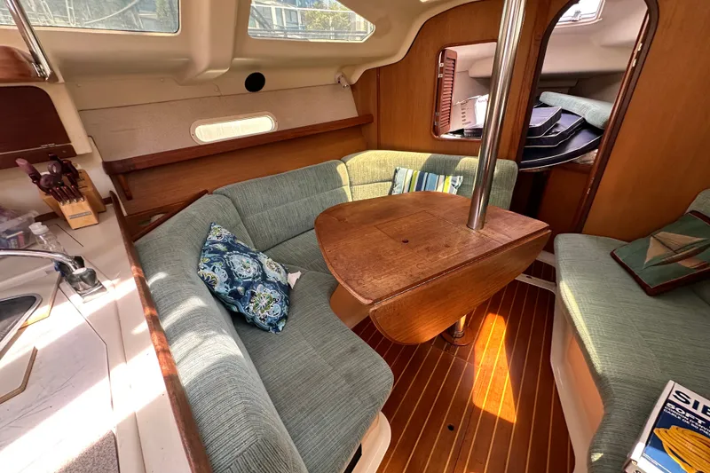Slide: The Image of Cozy interior of a 1997 Hunter 34 sailboat with cushioned seating and wooden table. - 23