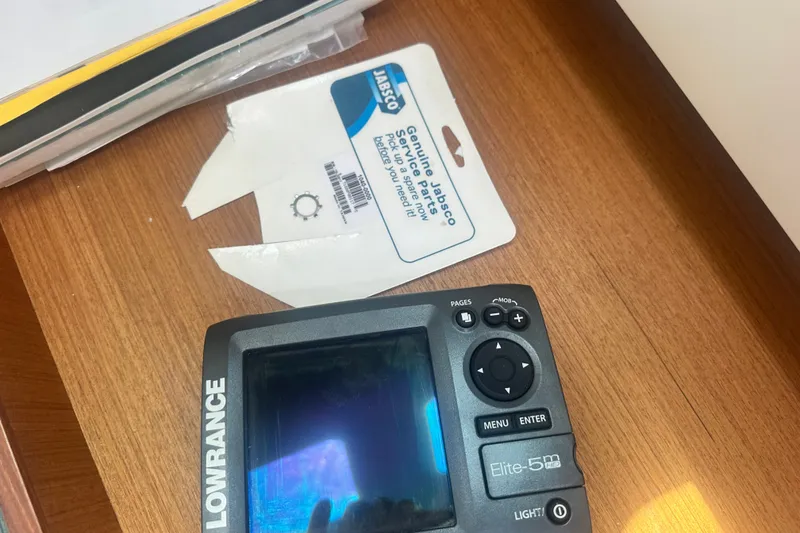 Slide: The Image of Lowrance Elite-5m GPS device and Jabsco service parts packaging on wooden surface. Hunter 34, 1997. - 20