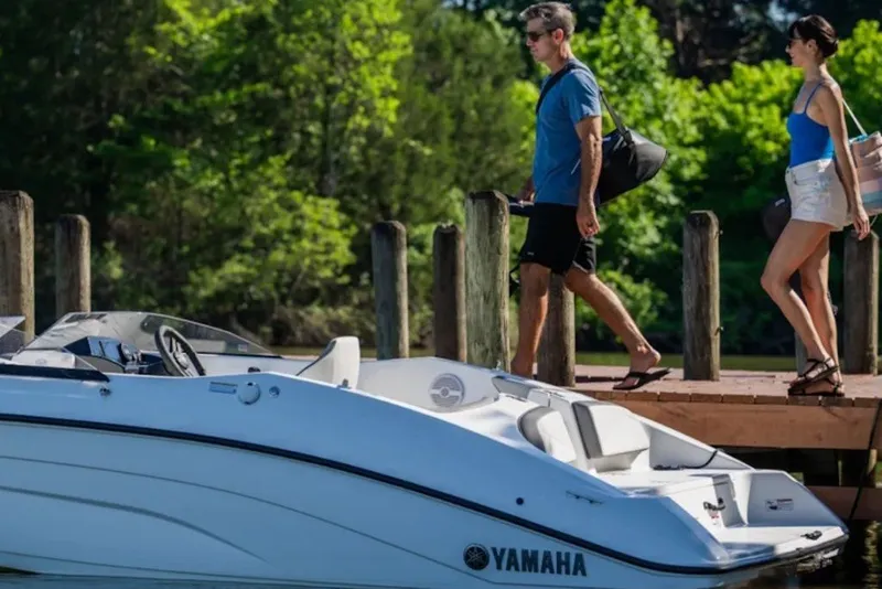 Slide: The Image of 2027 Yamaha Boats SX180 docked with two people walking nearby. - 2