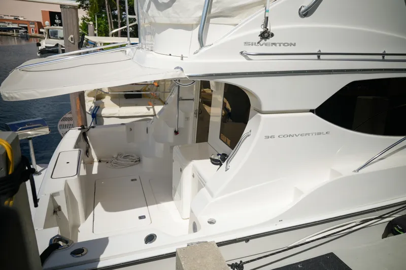 Slide: The Image of 2014 Silverton 36 Convertible yacht docked, showcasing sleek design and spacious deck area. - 2