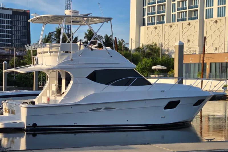 The Image of 2014 Silverton 36 Convertible yacht docked at a marina, with modern buildings in the background. - 0