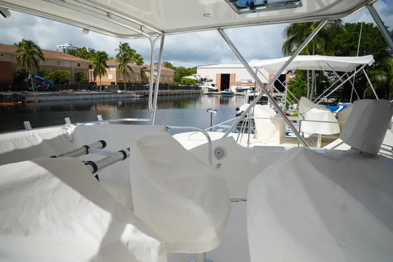 Slide: The Image of 2014 Silverton 36 Convertible yacht interior with marina view, featuring covered seating and helm. - 4