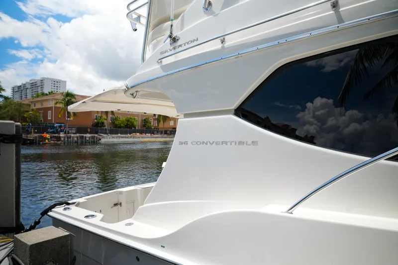 Slide: The Image of 2014 Silverton 36 Convertible yacht docked by waterfront buildings under a cloudy sky. - 31