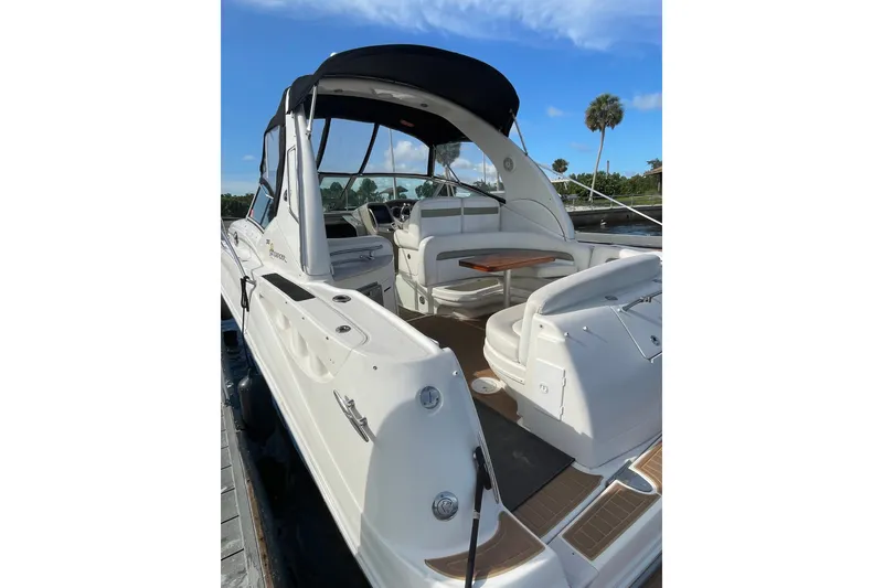 Slide: The Image of 2006 Sea Ray Sundancer 320 yacht with spacious deck and seating, docked under clear skies. - 4