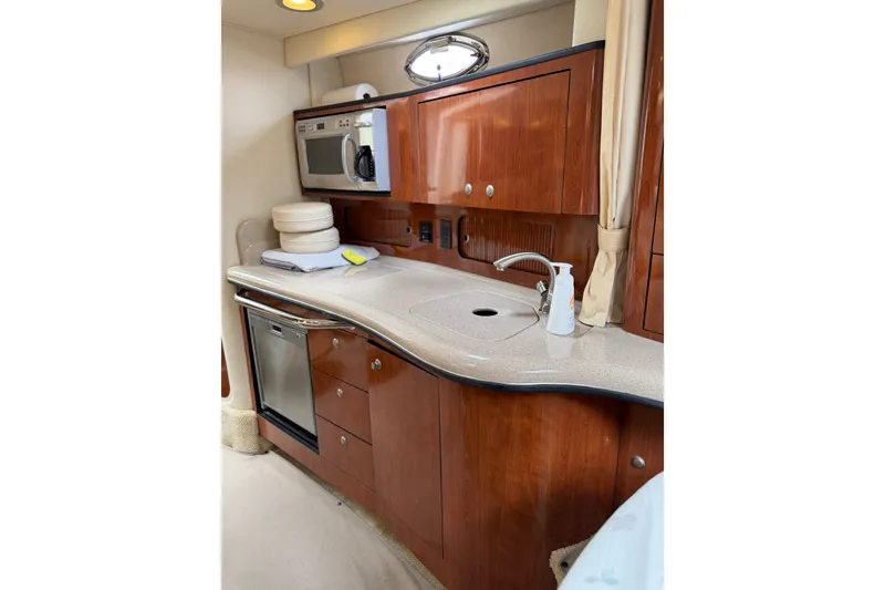 Slide: The Image of 2006 Sea Ray Sundancer 320 yacht kitchen with microwave, sink, and wooden cabinetry. - 15