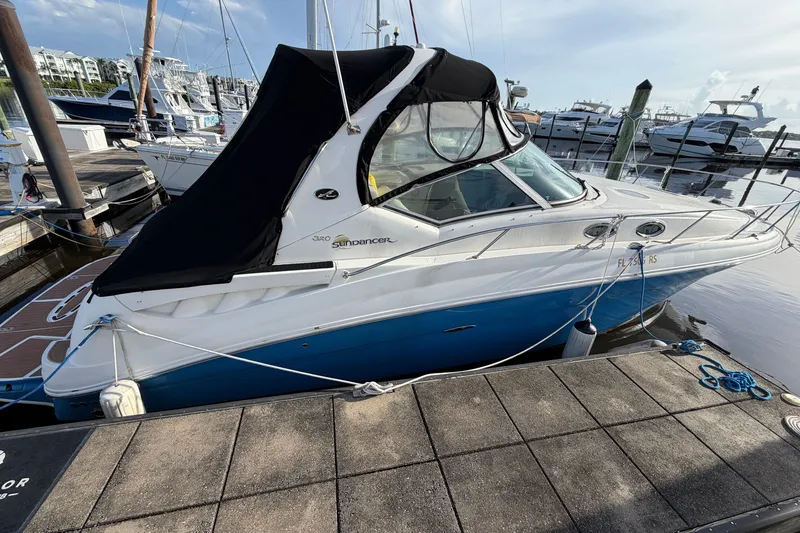 Slide: The Image of 2006 Sea Ray Sundancer 320 docked at marina, featuring sleek design and blue hull. - 27
