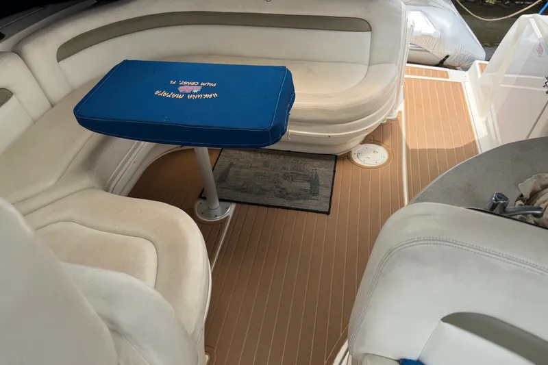 Slide: The Image of Interior of a 2006 Sea Ray Sundancer 320 boat with cushioned seating and a blue-covered table. - 10