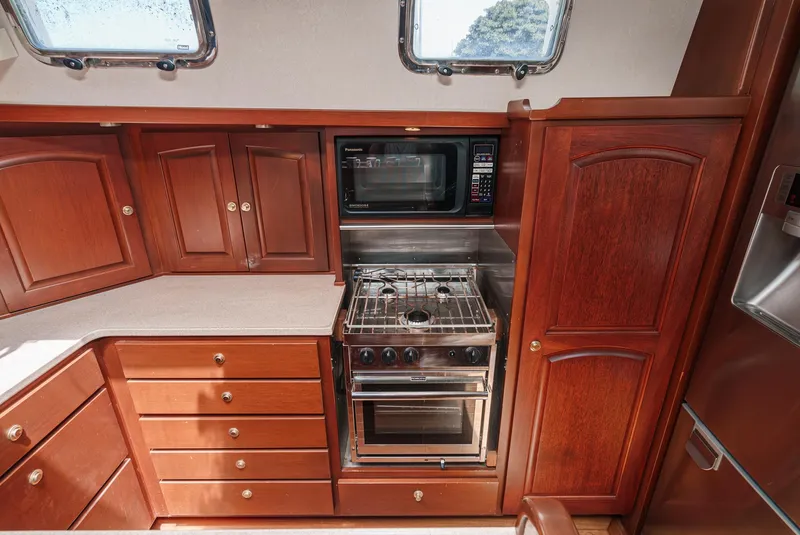 Slide: The Image of Philbrook's 69' Custom PH Sailing Sloop 1999 kitchen with wooden cabinets, stove, and microwave. - 41